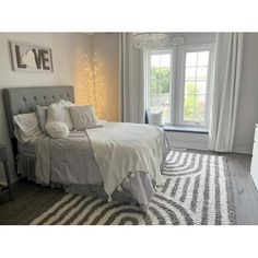 a white and gray bedroom with a large bed in the corner, window to the side