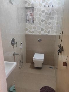 a bathroom with a toilet, sink and shower head mounted to the side of the wall