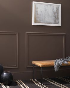 a wooden bench sitting in front of a wall with two vases and a painting on it