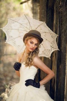 a woman in a white dress and hat holding an umbrella