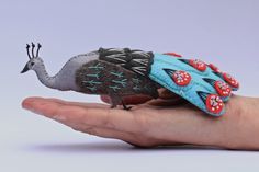 a hand holding a small bird on it's palm