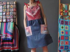 a woman standing in front of crocheted blankets and quilts on the wall