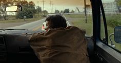 a man sitting in the driver's seat of a car looking out the window