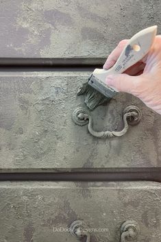 a hand with a brush on top of some drawers