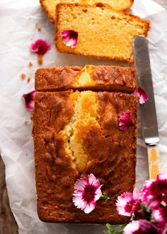 a loaf of lemon pound cake with flowers on the side and a knife next to it