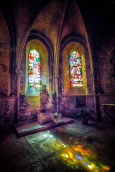 an old church with stained glass windows and a statue on the floor in front of it