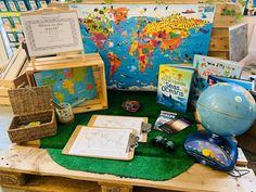 there are many books and other items on the wooden table in front of the map