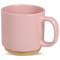 a pink coffee cup sitting on top of a wooden table