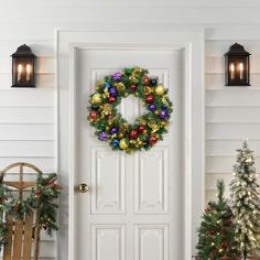 a christmas wreath on the front door of a house decorated with holiday decorations and lights