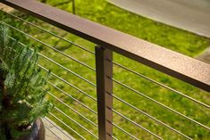 a potted plant sitting on the side of a metal railing next to a sidewalk