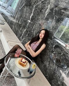 a woman sitting on a bench next to a table with food and drinks in front of her