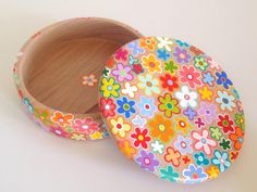 a wooden box with colorful flowers painted on the lid and inside, sitting on a white surface