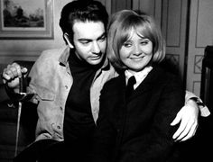 black and white photo of man and woman sitting on couch with arm around each other