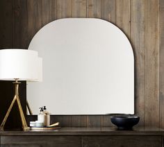 a mirror sitting on top of a dresser next to a lamp