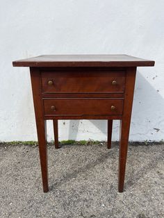 a small wooden table with two drawers on one side and an open drawer on the other