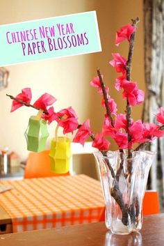 a vase filled with pink flowers sitting on top of a table next to a sign that says chinese new year paper blossoms