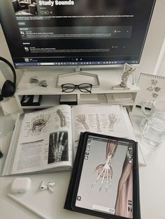 an open book sitting on top of a desk next to headphones and a computer monitor