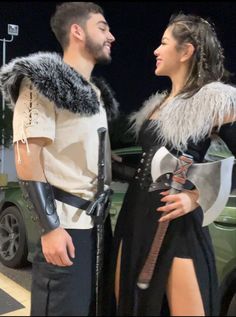 a man and woman dressed up in costumes standing next to each other near a car