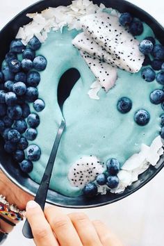 a person is holding a cake with blueberries and cream on it while wearing a watch