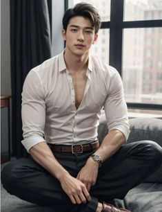 a young man sitting on top of a couch wearing a white shirt and black pants