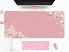 a pink mouse pad with flowers on it next to a computer keyboard and headphones