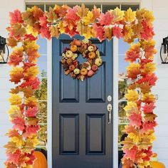 a front door decorated with fall leaves and pumpkins