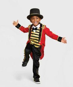 a young boy dressed in a red and gold costume with his hands out to the side