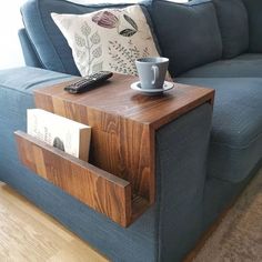 a blue couch with a coffee cup and remote control on it's end table