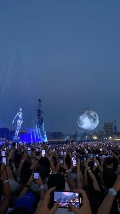 a large group of people taking pictures with their cell phones in front of the stage