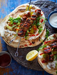 two pita breads with skewered meat and veggies on them