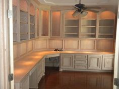 an empty kitchen with white cabinets and wood flooring in the middle of the room