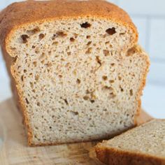 a loaf of bread sitting on top of a wooden cutting board next to a slice of bread