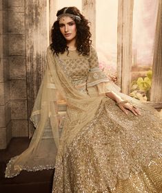 COLOR : Beige Gold FABRIC : Top (Blouse) - Net, Bottom (Lehenga) - Net, Inner - Santoon & Satin, Dupatta - Net WORK : Heavy Zari & Silk Thread Embroidery, Sequins, Stones, Pearls, Motifs, Beads, Tassels, Lace Border OCCASION : Wedding, Reception, Sangeet, Engagement READY-TO-WEAR : NoSTITCHING : Available as semi-stitched fabric, can be stitched using standard size option (+$30). Note: There might be a slight color variation due to lighting and flash used during photoshoot. The bright shade seen Bridesmaid Lehenga, Indian Lehenga Choli, Indian Party Wear, Net Lehenga, Bridal Lehengas, Ghagra Choli, Indian Lehenga, Party Wear Lehenga, Bridal Lehenga Choli