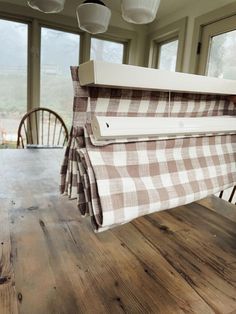 a brown and white checkered table cloth hanging from a light fixture over a wooden dining room table