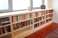 a bookshelf filled with lots of books on top of a hard wood floor