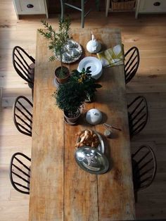 an overhead view of a wooden table with chairs and dishes on it, in the middle of a wood floored dining room