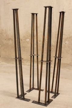 three metal poles are standing next to each other on the cement floor in front of a wall