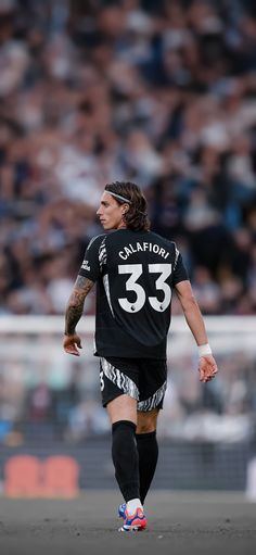 a soccer player is running with the ball in his hand and looking at the crowd