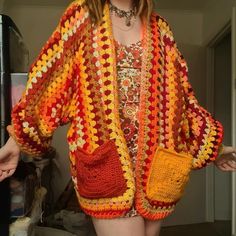 a woman is wearing a crocheted jacket and holding her hand on her hip