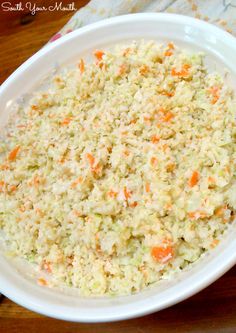 a bowl filled with coleslaw and carrots on top of a wooden table