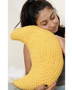 a woman is holding a crocheted banana pillow