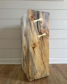 a wooden box sitting on top of a hard wood floor next to a white wall