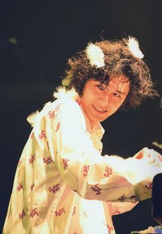 a man with curly hair is smiling at the camera while he plays an electric piano