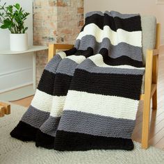 a black and white blanket sitting on top of a chair next to a potted plant