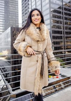 Delivering huge fashion impact with maximum warmth, our Dakota Fox coat SCORES! In luxe Latte vegan suede, the supple, soft hand ensures a fluid, compact silhouette. A luxurious Taupe Fox collar adds lush, plush warmth, along with the bonus of a strong shoulder. Continuing along the center front to the hem, this super-soft fur adds style AND verticality. With Chocolate tipping for authenticity, Taupe Fox is repeated in the adjustable cuffs. Inside a sheared fur lining provides welcome warmth while body-skimming princess seams front and back, provide a lean fit. Bold Chocolate whipstitching accents the flap pockets, sleeve belts, the boundless details and seaming! A tie belt, worn either front or back, pulls together this 37" coat that hints of effortless elegance and quiet confidence. Perf Fall Long Pea Coat With Faux Fur Lining, Chic Fall Wool Coat With Faux Fur Lining, Elegant Sheepskin Outerwear For Fall, Chic Cold Weather Fur Coat With Faux Fur Trim, Chic Wool Coat With Faux Fur Lining For Winter, Chic Mink-colored Outerwear With Faux Fur Lining, Chic Mink Outerwear With Faux Fur Lining, Chic Mink Color Outerwear With Faux Fur Lining, Elegant Faux Fur Outerwear For Fall