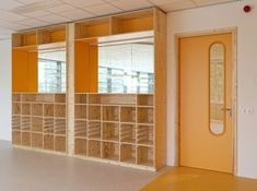 an empty room with wooden shelves and mirrors on the wall, in front of a yellow door