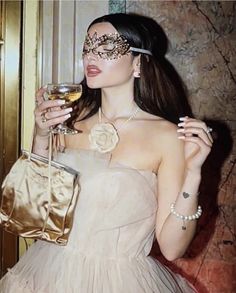 a woman in a masquerade holding a glass of wine