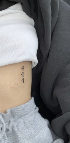 a woman with a small tattoo on her lower side ribcage that says aha