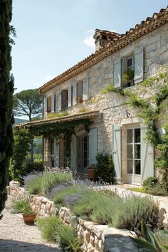 an old stone house with lots of greenery