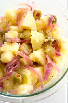 a bowl filled with pineapple and red onion salad on top of a white table